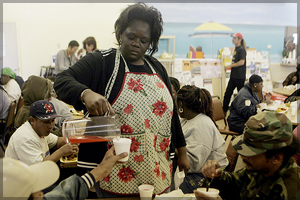 Example of a soup kitchen: a worker serving a glass of water to a man.